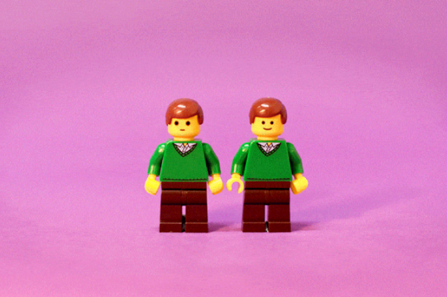 Two lego men smiling against a pink background