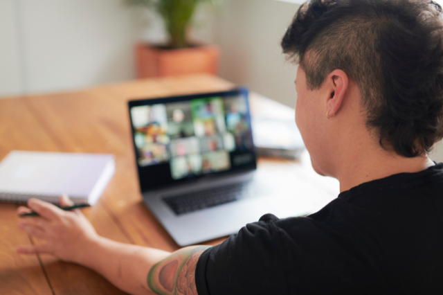 Photo of an individual sat in front of a laptop on a virtual meeting.